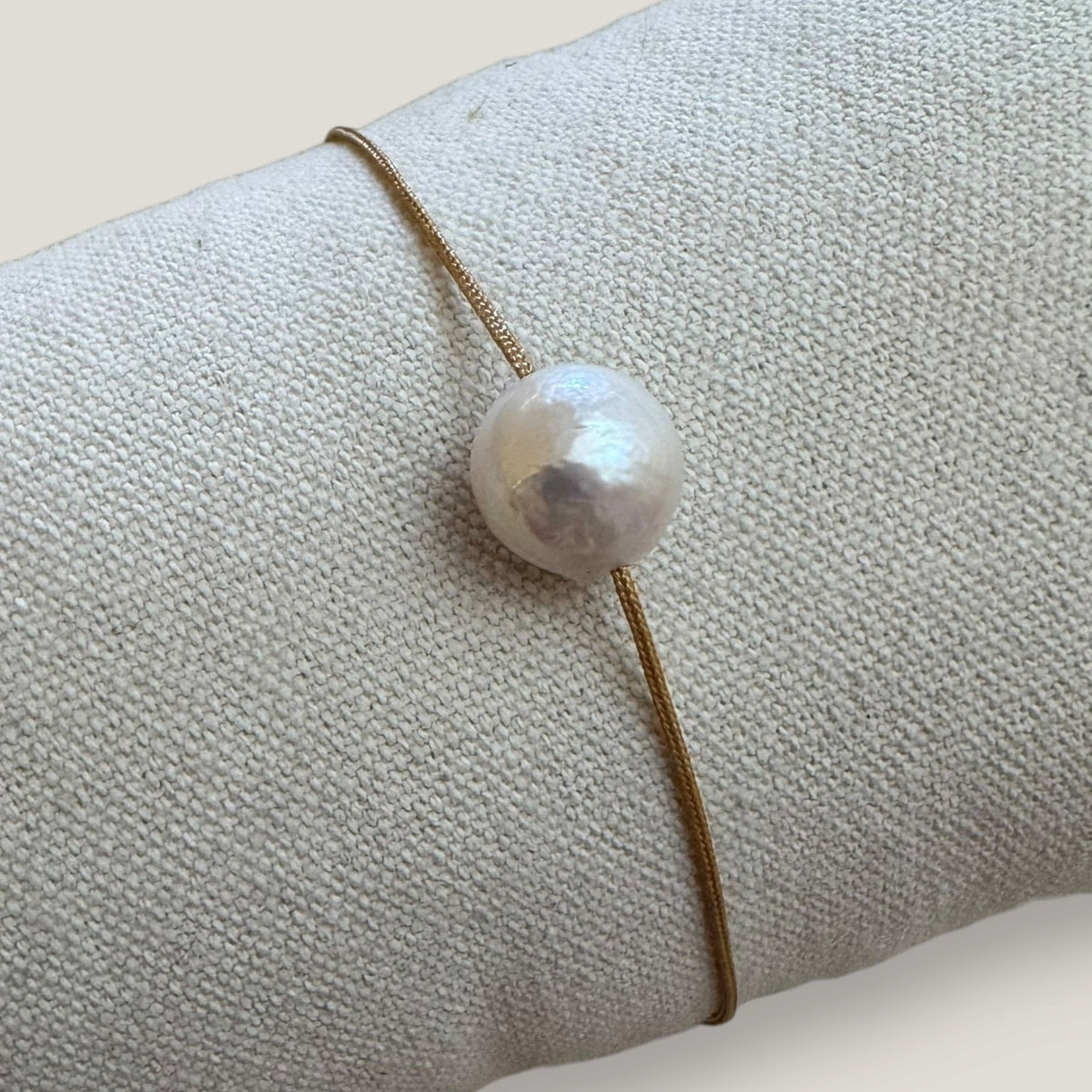Pulsera minimal perla natural redondeada 10mm blanca cordón nailon dorado