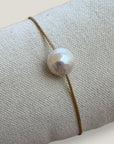 Pulsera minimal perla natural redondeada 10mm blanca cordón nailon dorado