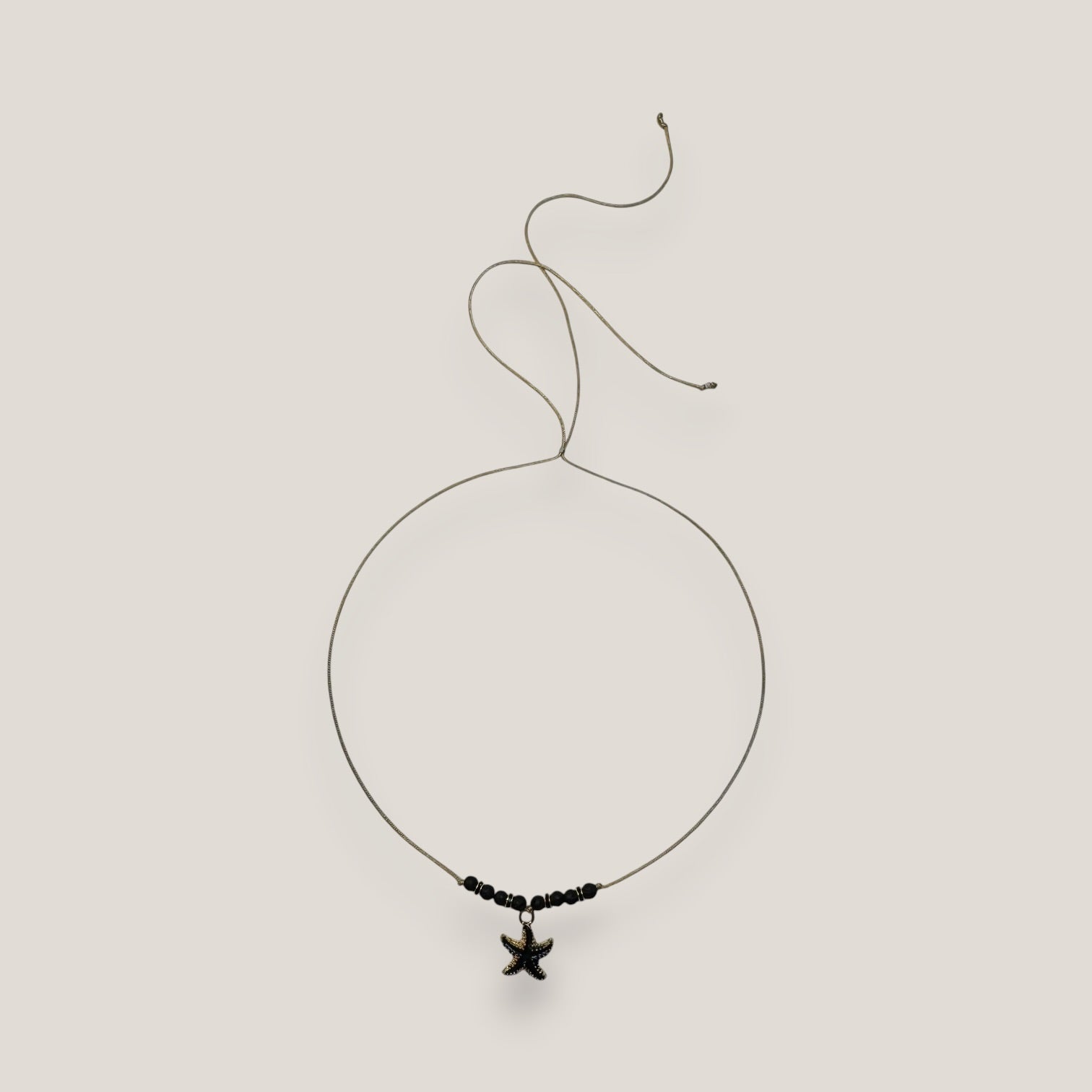 Collar midi con estrella dorada esmaltada en negro lava negra y separadores dorados con cristalitos negros