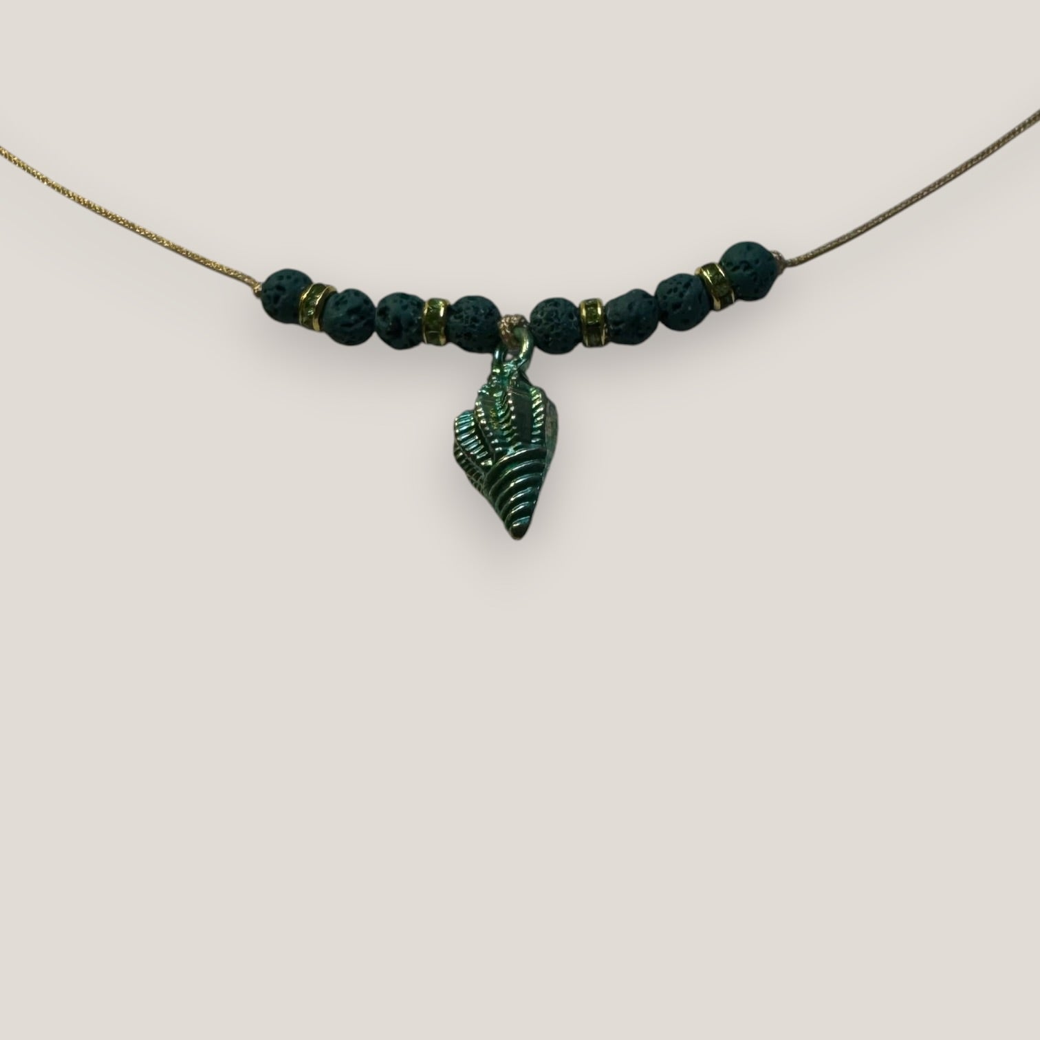 Collar midi con caracola dorada esmaltada en verde con lava verde oscuro y separadores dorados con cristalitos verde olivina