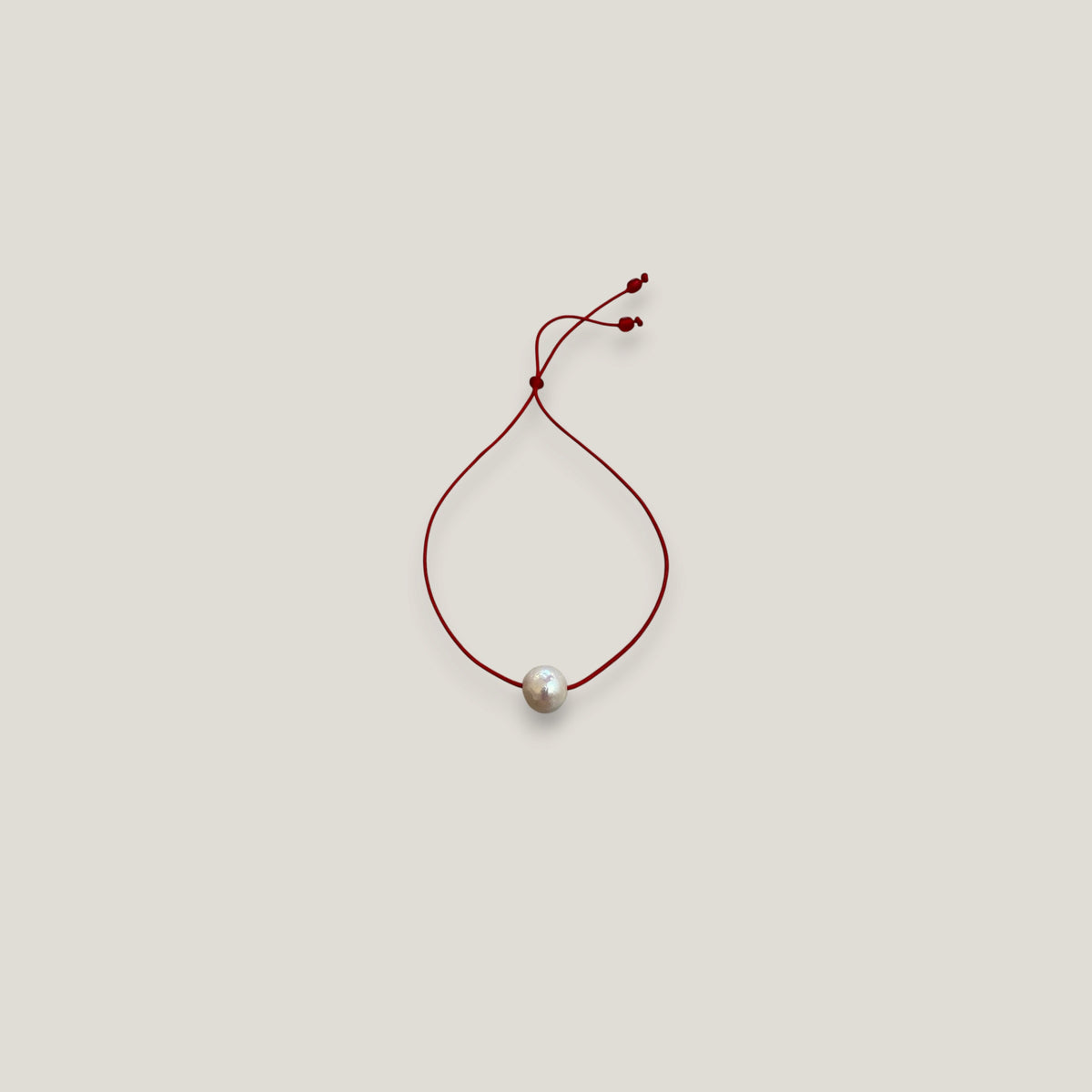Pulsera minimal perla natural redondeada 10mm blanca cordón nailon rojo
