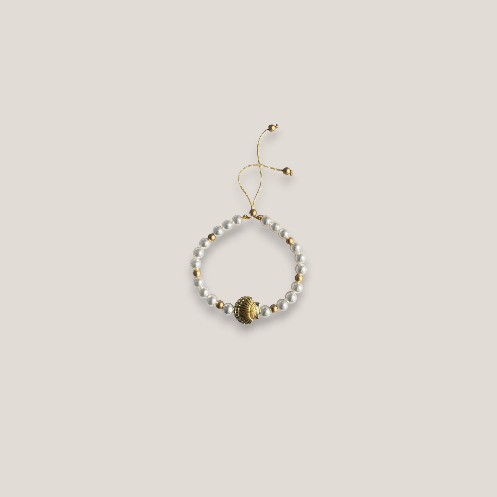 Armband mit großer goldener Muschel und weißen Glasperlen