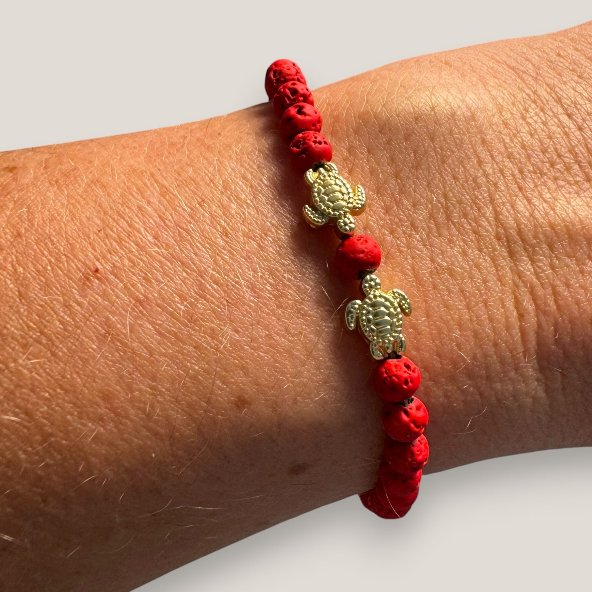 Armband mit goldenen Liebesschildkröten und roter Lava