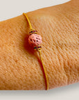 Pulsera minimal con bola de lava fucsia y cuentas doradas con brillis rosas