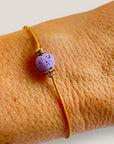 Pulsera minimal con bola de lava malva y cuentas doradas con brillis rosas