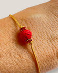 Pulsera minimal con bola de lava roja y cuentas doradas con brillis rojos