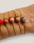 Pulsera minimal con bola de lava rosa y cuentas doradas con brillis rosas