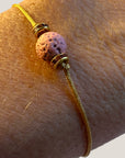 Pulsera minimal con bola de lava rosa y cuentas doradas con brillis rosas